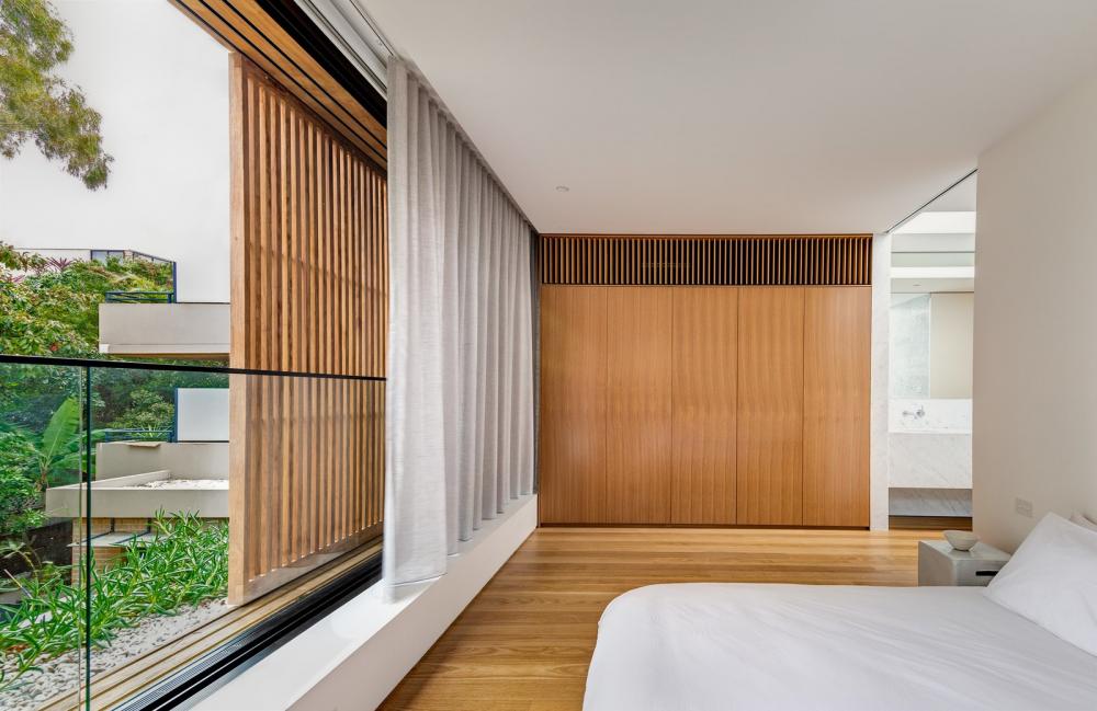 Phòng ngủ chính có cửa sổ trượt và màn che riêng tư trải khắp chiều rộng của ngôi nhà